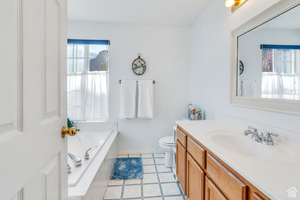 Bathroom featuring toilet, tile flooring, tiled bath, and large vanity