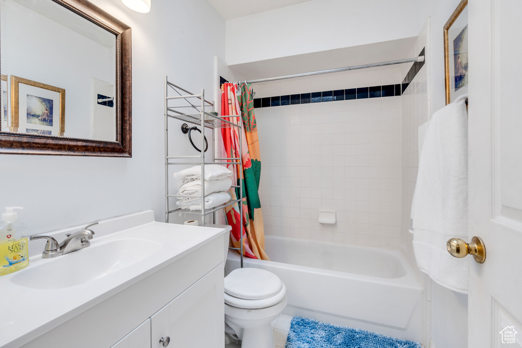 Full bathroom with shower / bath combo, toilet, large vanity, and tile floors