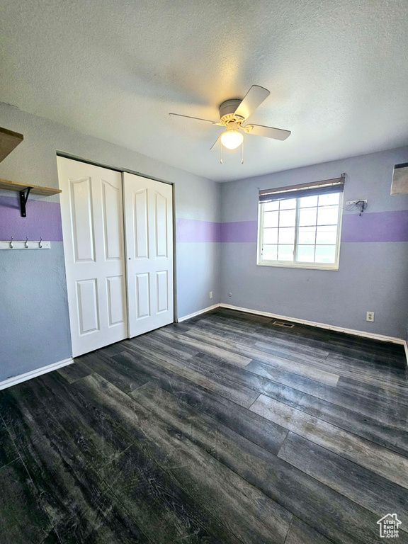 Unfurnished bedroom featuring dark hardwood / wood-style flooring, ceiling fan, a closet, and a textured ceiling