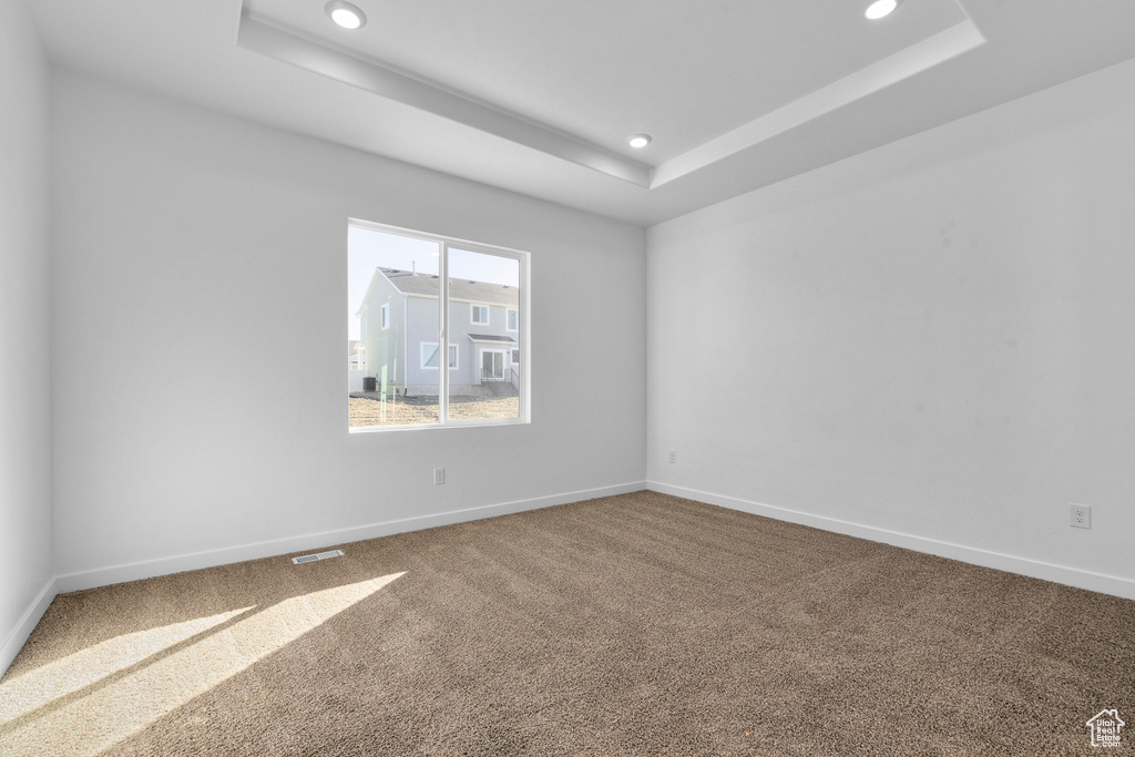 Empty room featuring carpet and a raised ceiling