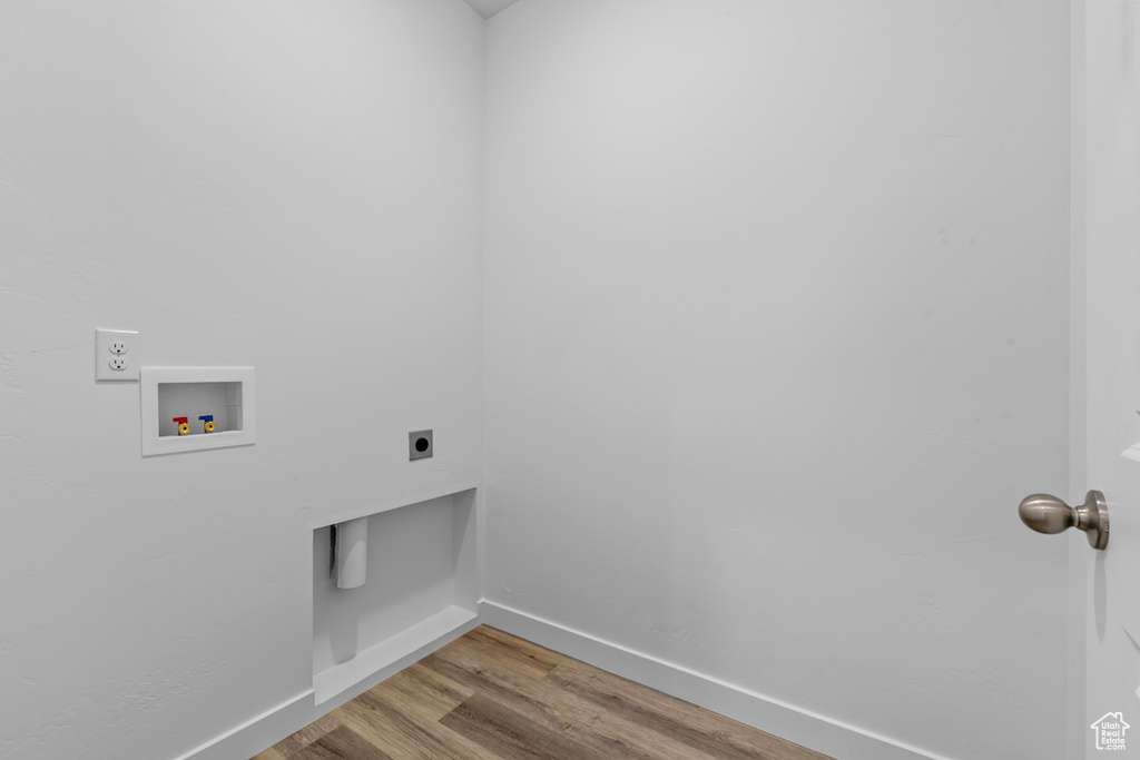 Washroom with hookup for an electric dryer, hardwood / wood-style flooring, and washer hookup
