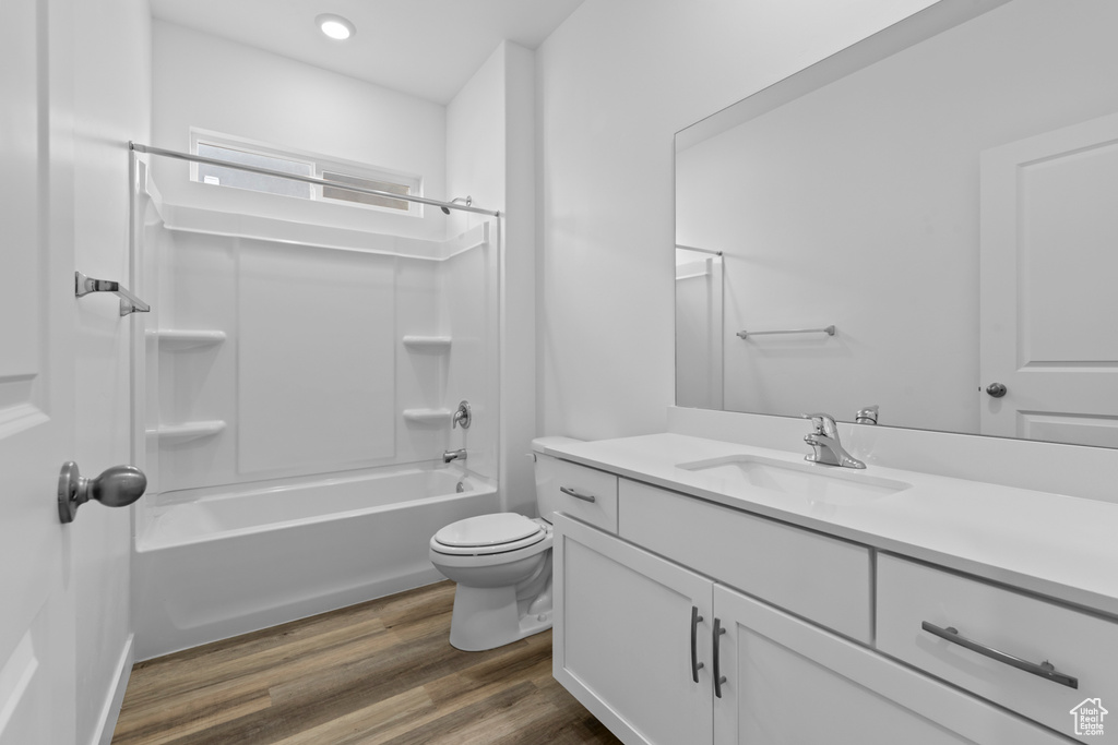 Full bathroom with hardwood / wood-style flooring, shower / bath combination, toilet, and vanity with extensive cabinet space
