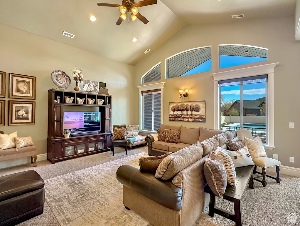 Living room featuring high vaulted ceiling, ceiling fan, and carpet floors