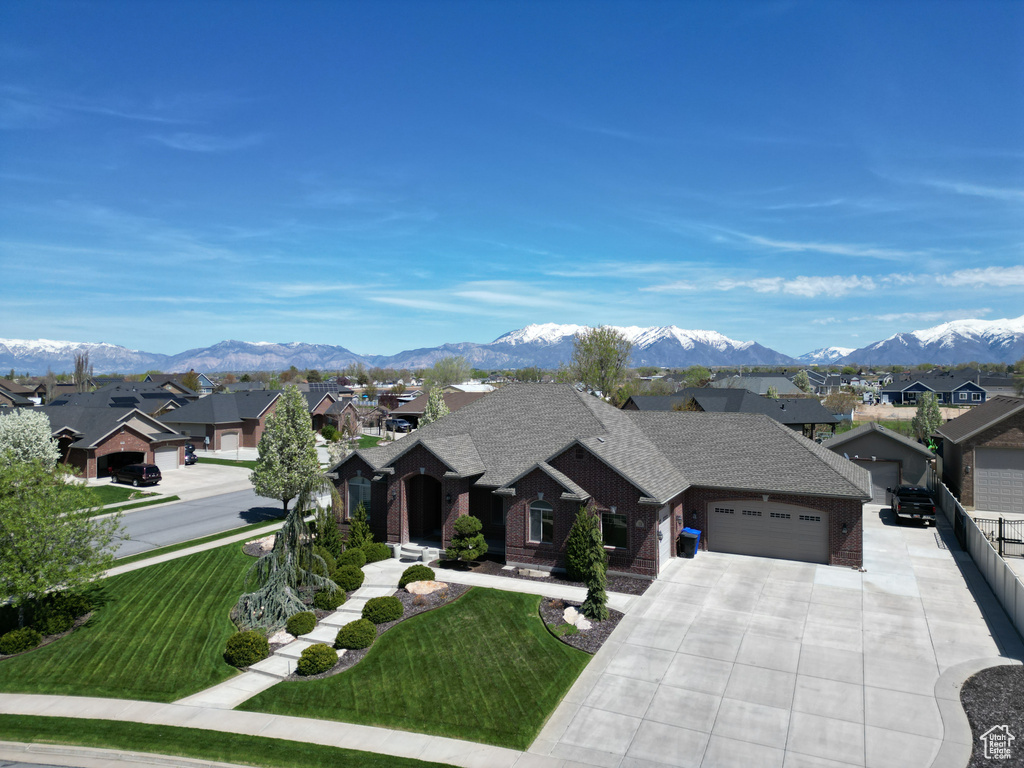 View of front of property featuring a mountain view, a front lawn, and a garage
