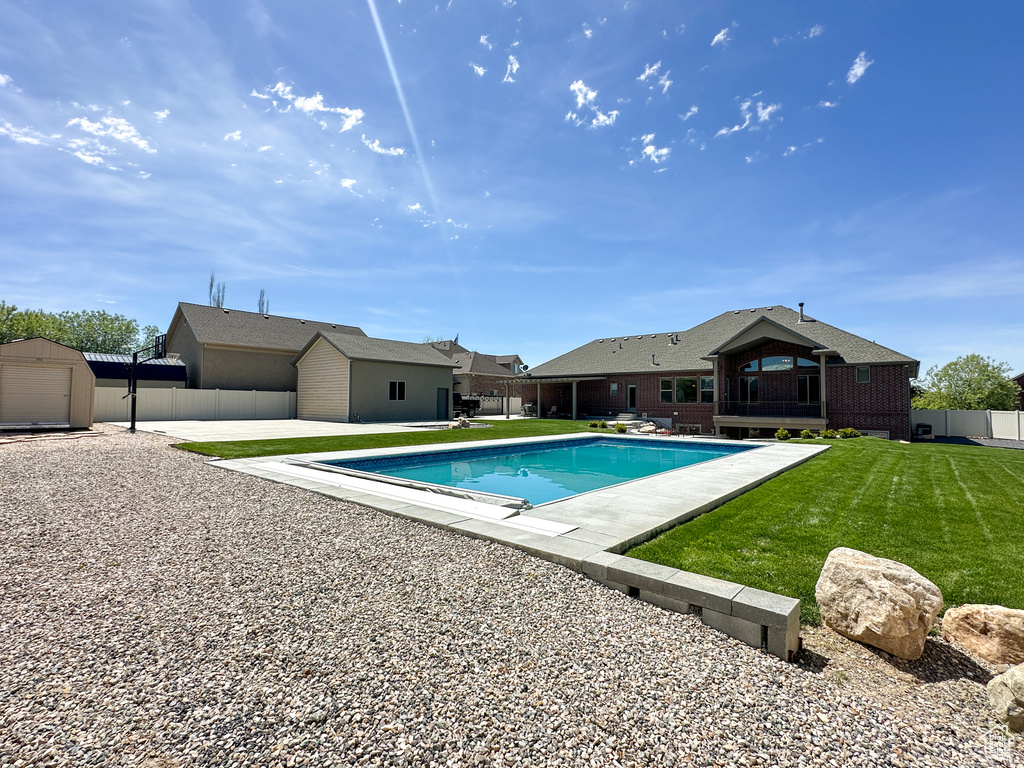 View of pool featuring a patio, a yard, and a storage unit