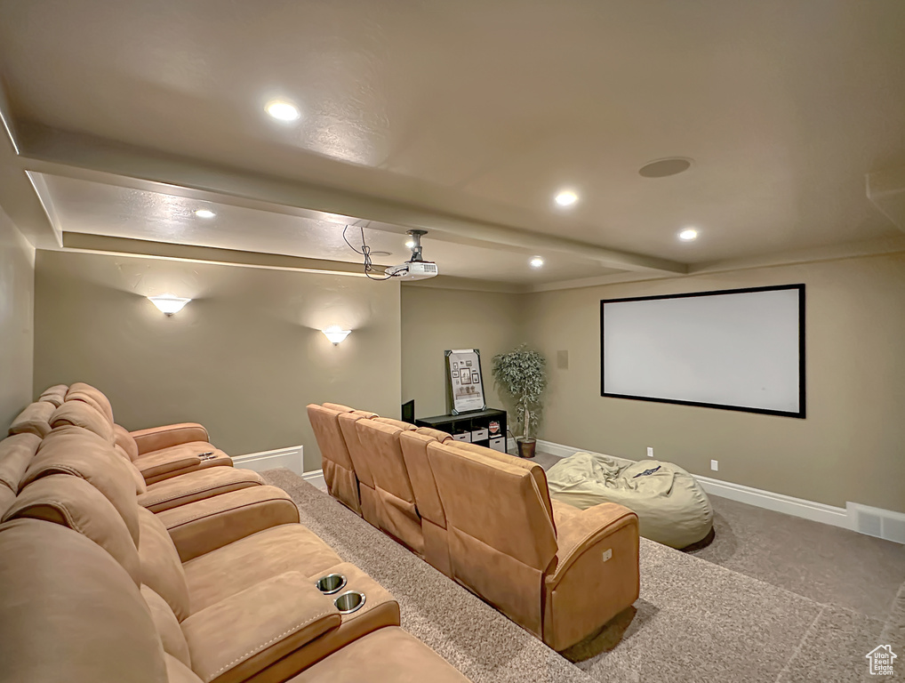 Home theater room featuring beamed ceiling and carpet floors