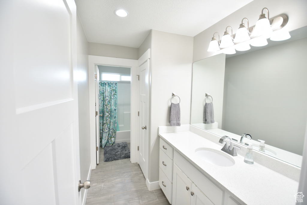 Bathroom featuring oversized vanity and shower / tub combo with curtain