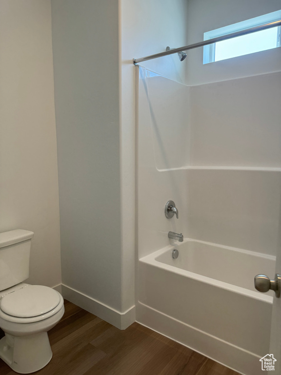 Bathroom featuring wood-type flooring, shower / bathtub combination, and toilet