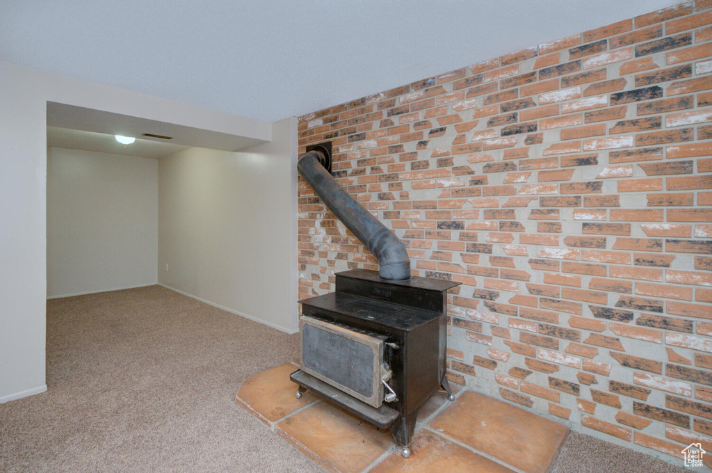 Carpeted living room with brick wall and a wood stove