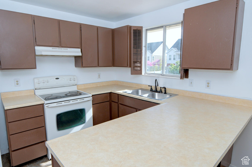 Kitchen featuring kitchen peninsula, sink, and white electric range