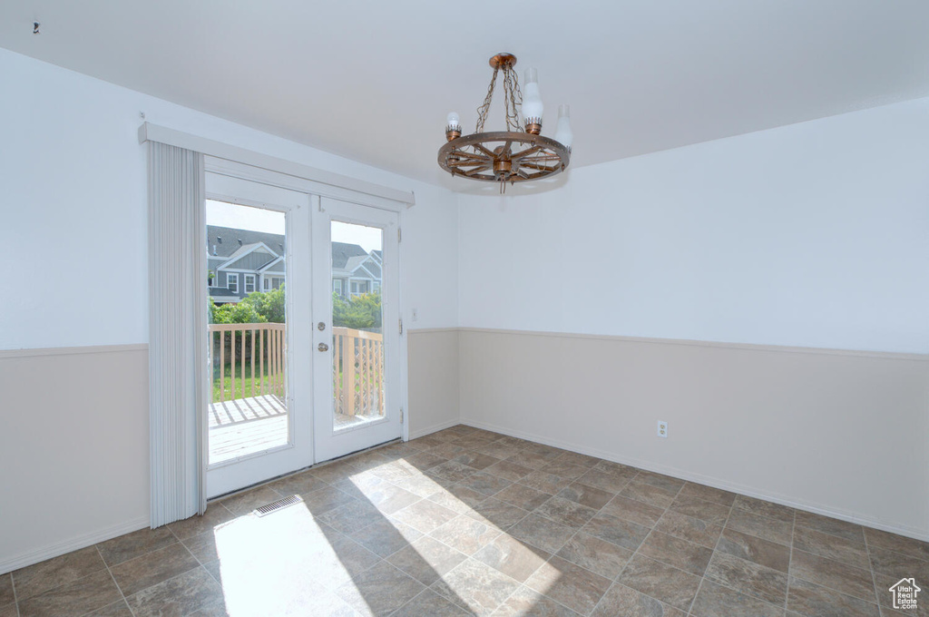 Unfurnished room featuring french doors, an inviting chandelier, and tile flooring