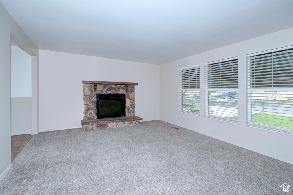 Unfurnished living room featuring carpet and a stone fireplace
