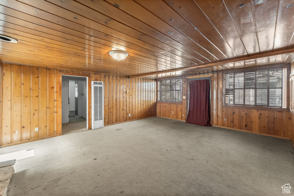 Carpeted spare room with wood ceiling and wood walls