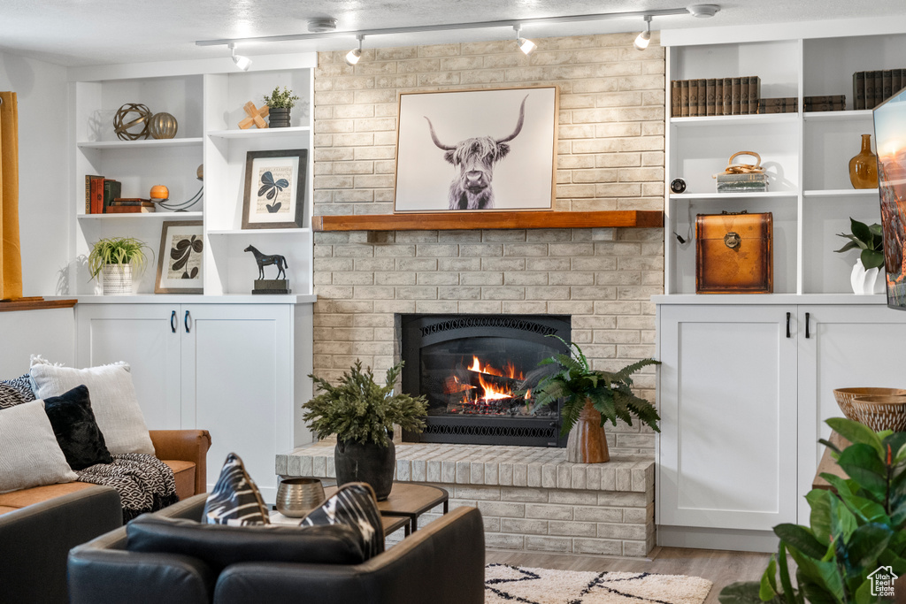 Living room featuring light hardwood / wood-style flooring, a brick fireplace, and rail lighting