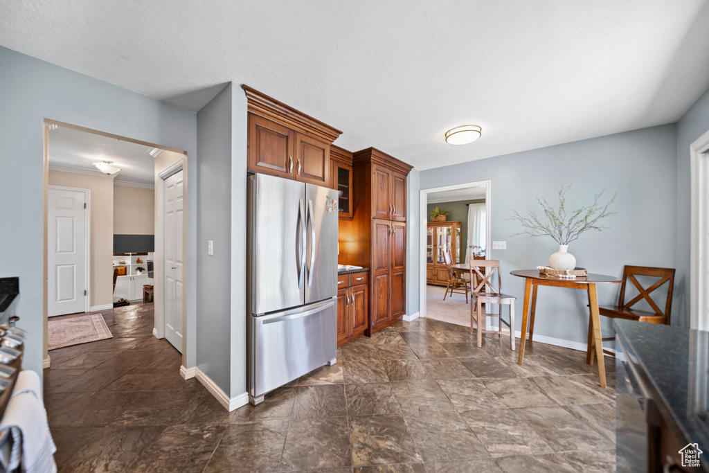 Kitchen featuring stainless steel refrigerator, crown molding, and dark tile floors
