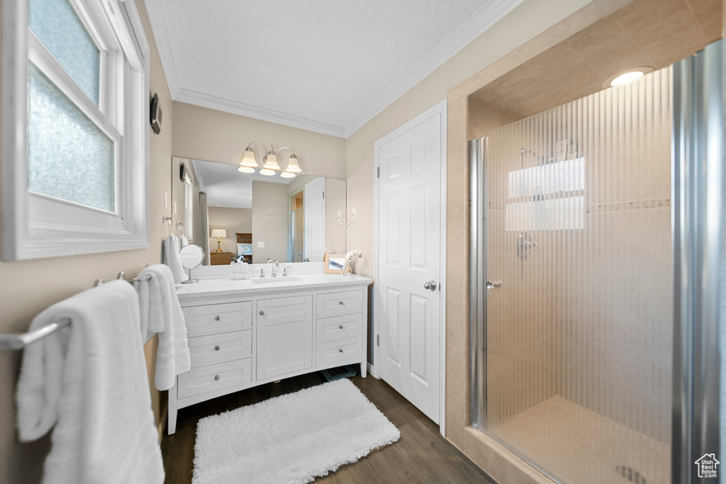 Bathroom featuring hardwood / wood-style floors, ornamental molding, vanity, and a shower with door