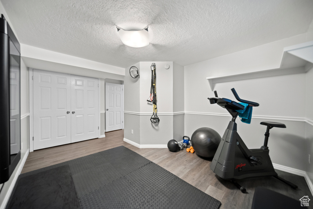 Exercise area featuring hardwood / wood-style flooring and a textured ceiling
