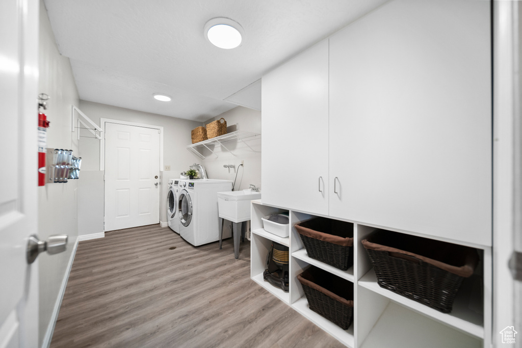 Laundry room featuring hardwood / wood-style flooring, cabinets, sink, and washer and dryer
