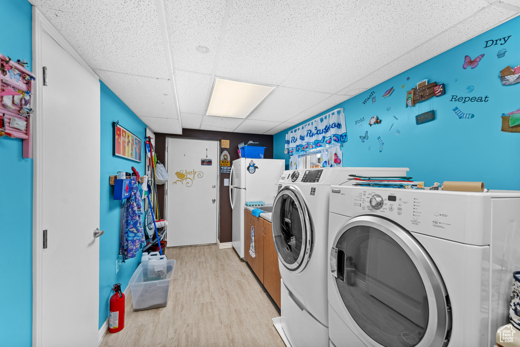 Laundry area with light wood-type flooring and washing machine and clothes dryer