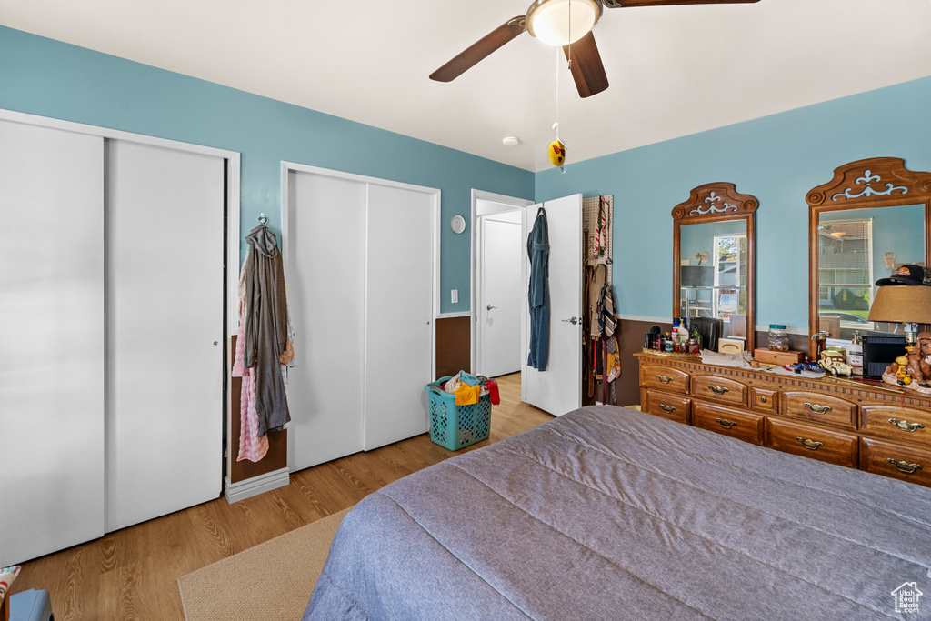 Bedroom featuring light hardwood / wood-style floors, ceiling fan, and two closets