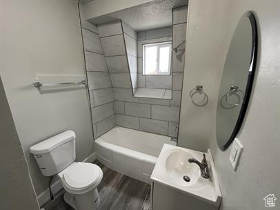 Full bathroom with large vanity, toilet, hardwood / wood-style flooring, and tiled shower / bath