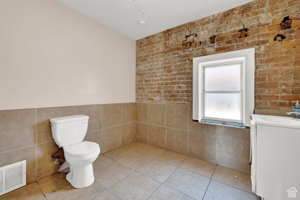 Bathroom with tile walls, toilet, tile floors, and vanity