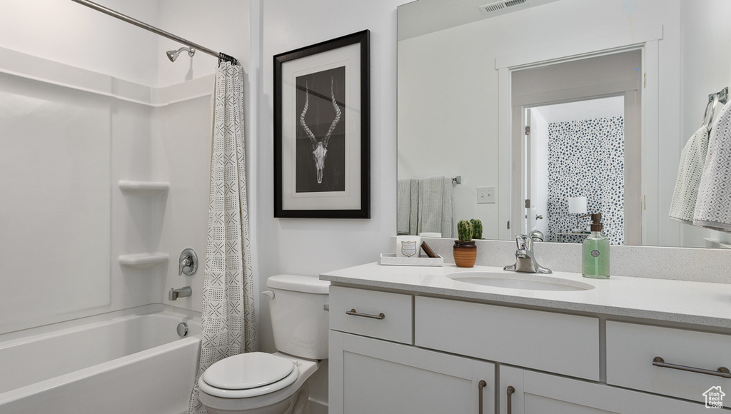 Full bathroom with toilet, large vanity, and shower / tub combo with curtain