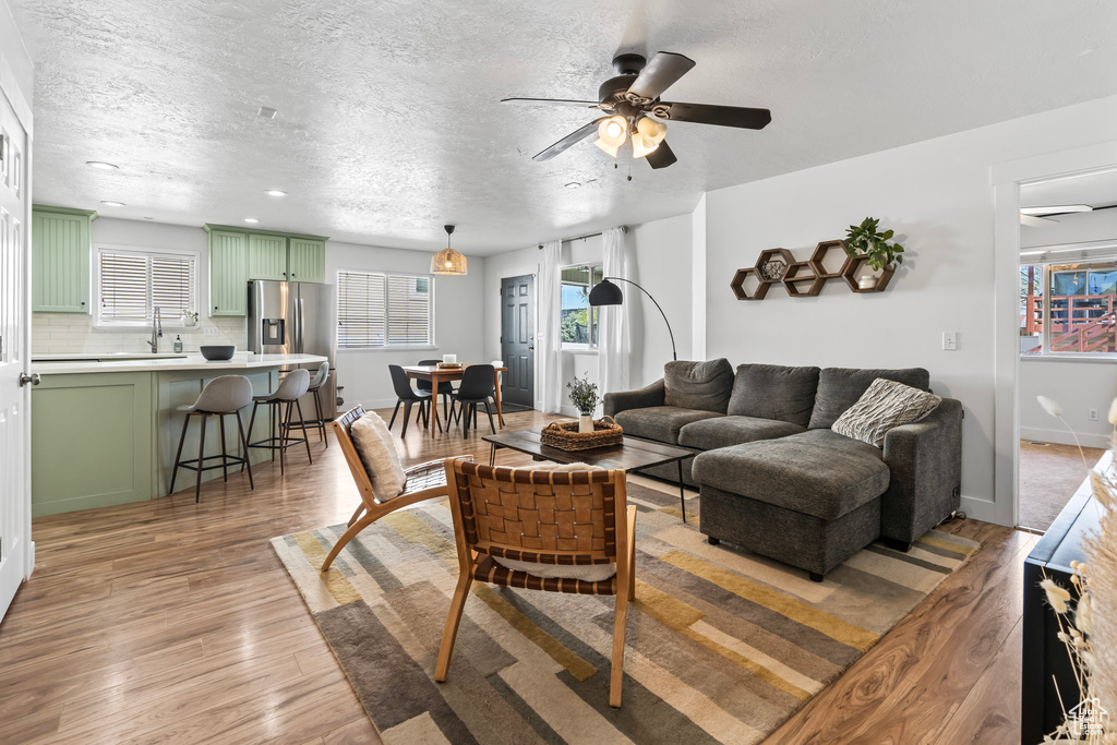 Living room featuring ceiling fan, hardwood / wood-style flooring, and a textured ceiling