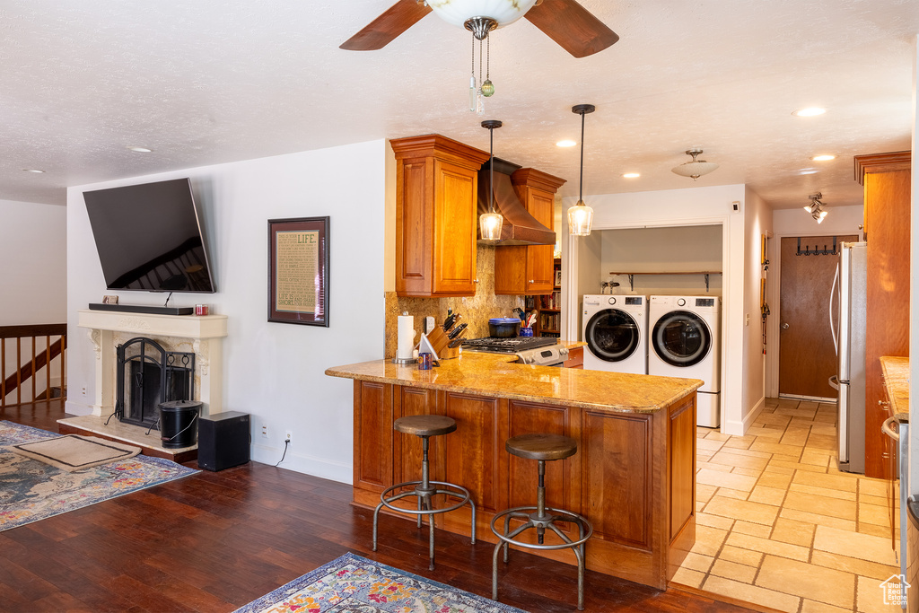 Kitchen featuring hanging light fixtures, separate washer and dryer, backsplash, kitchen peninsula, and ceiling fan