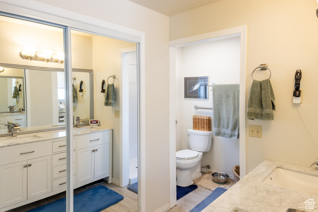Bathroom with hardwood / wood-style floors, dual vanity, and toilet