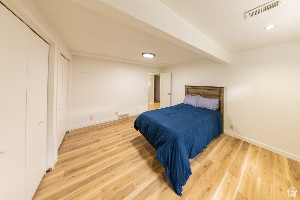 Bedroom with beamed ceiling and light hardwood / wood-style flooring