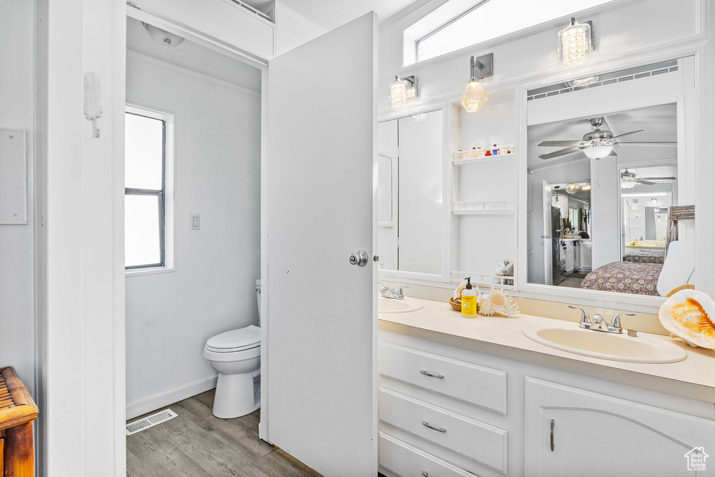 Bathroom with plenty of natural light, vanity, hardwood / wood-style flooring, toilet, and ceiling fan
