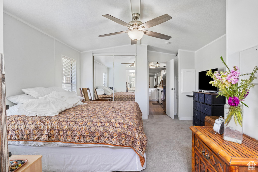 Carpeted bedroom with crown molding, ceiling fan, a closet, and vaulted ceiling