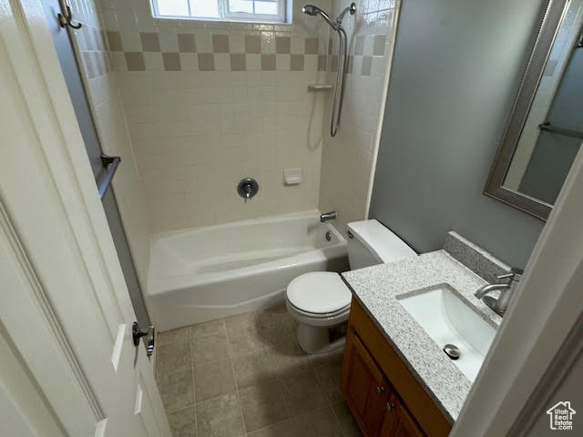 Full bathroom featuring tiled shower / bath combo, large vanity, tile floors, and toilet
