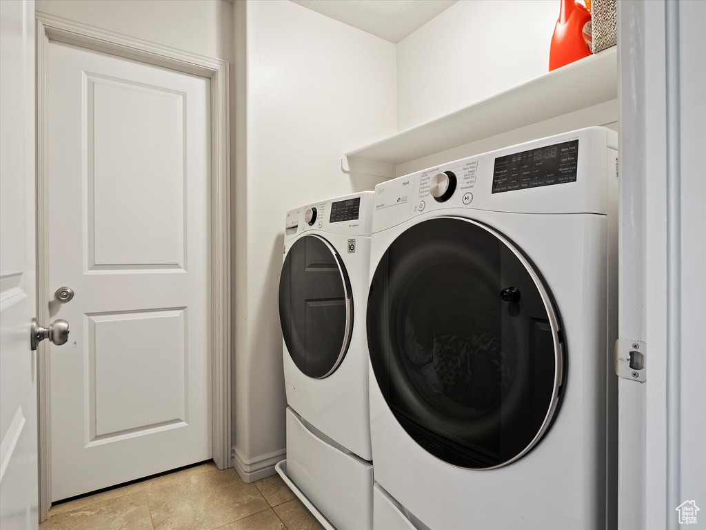 Laundry room featuring washing machine and dryer and light tile floors