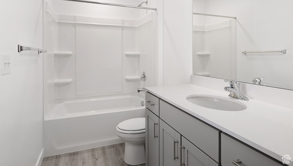 Full bathroom with wood-type flooring, shower / tub combination, vanity with extensive cabinet space, and toilet