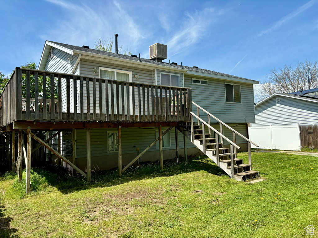 Rear view of house with a deck and a yard