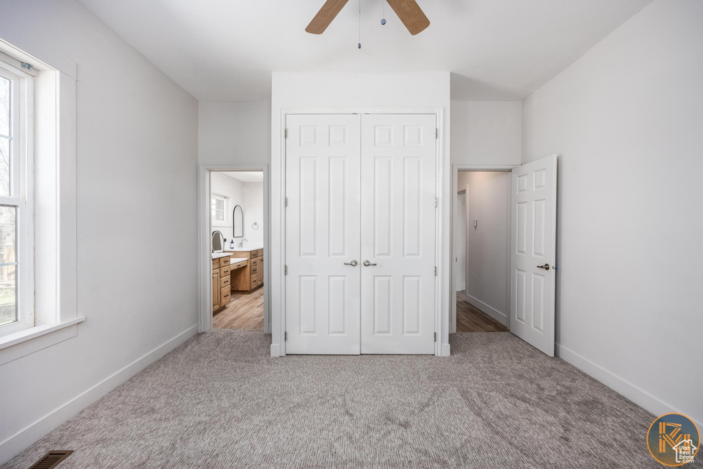 Unfurnished bedroom featuring light carpet, a closet, ceiling fan, and multiple windows