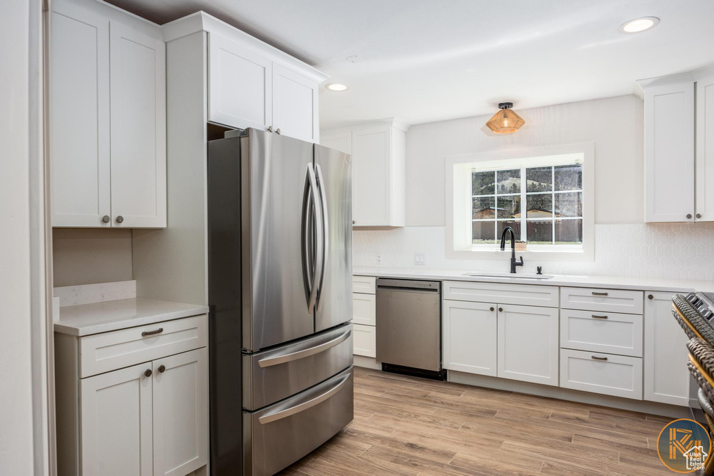 Kitchen featuring sink, appliances with stainless steel finishes, light wood-type flooring, and white cabinetry