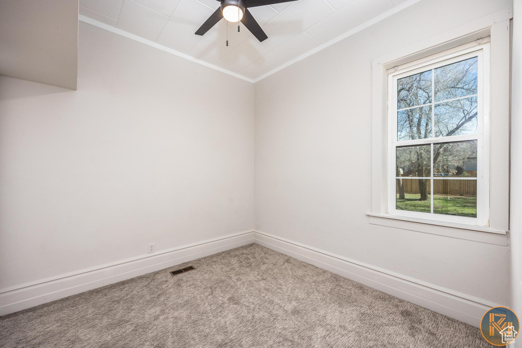 Empty room featuring ceiling fan, carpet, and ornamental molding