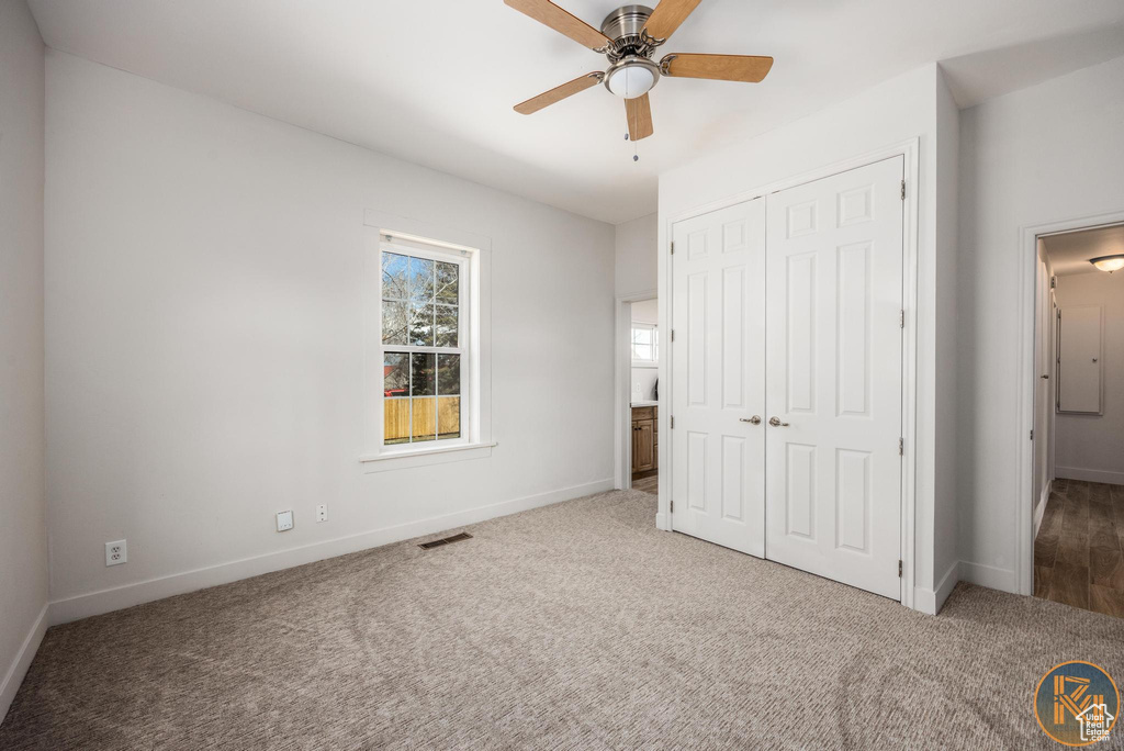 Unfurnished bedroom with carpet, ceiling fan, and a closet