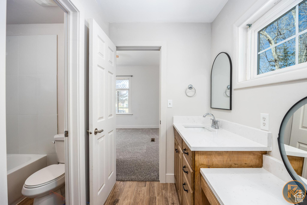 Full bathroom with vanity, toilet, hardwood / wood-style flooring, and  shower combination