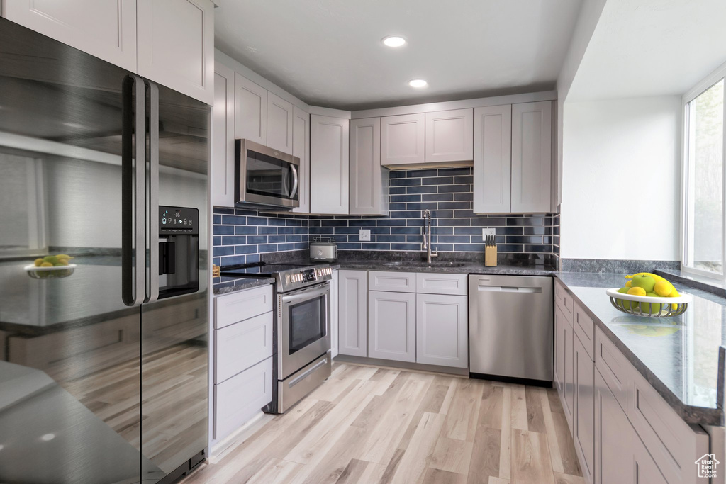 Kitchen featuring sink, light hardwood / wood-style floors, backsplash, and stainless steel appliances