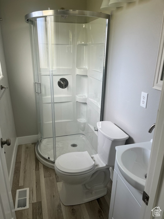 Bathroom with a shower with door, hardwood / wood-style floors, vanity, and toilet