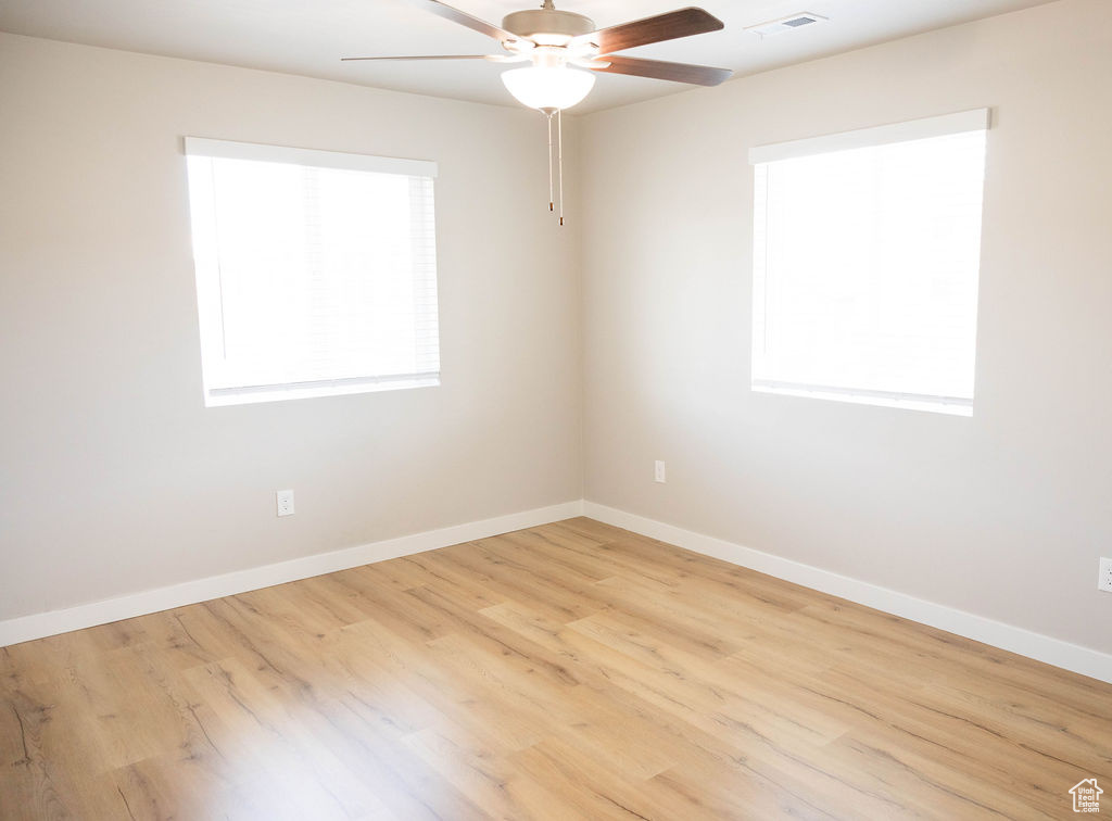 Empty room featuring light hardwood / wood-style flooring, ceiling fan, and plenty of natural light
