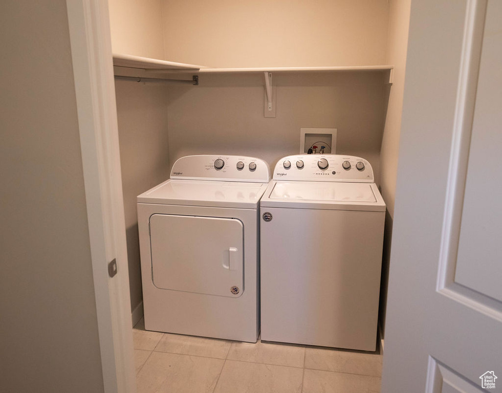 Laundry area with light tile floors, hookup for a washing machine, and washer and dryer