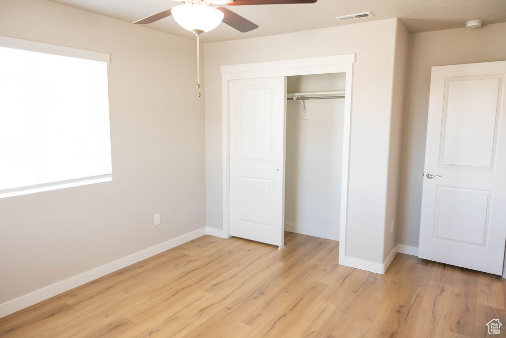 Unfurnished bedroom with light hardwood / wood-style flooring, ceiling fan, and a closet