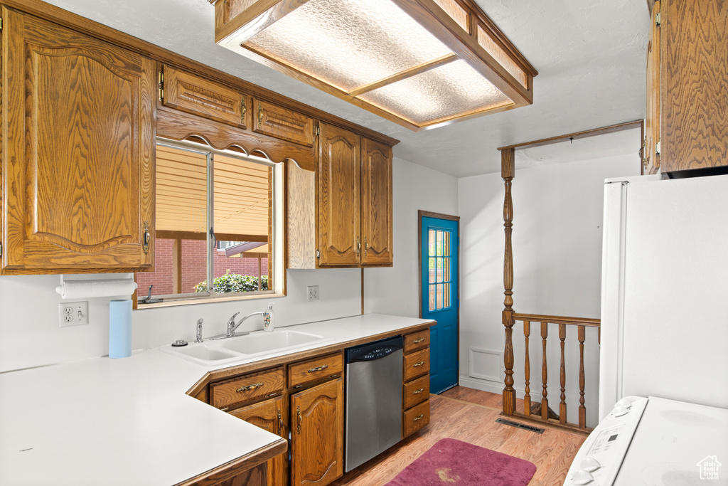 Kitchen with light hardwood / wood-style floors, dishwasher, stove, sink, and white refrigerator