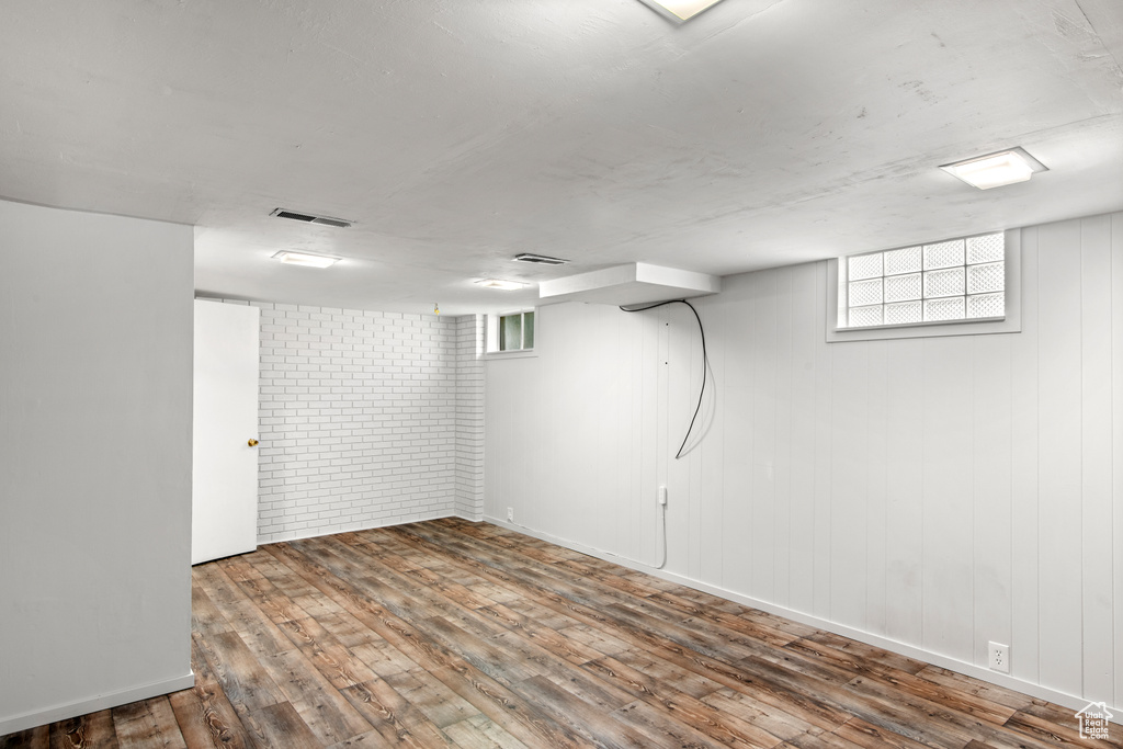 Basement with brick wall and wood-type flooring
