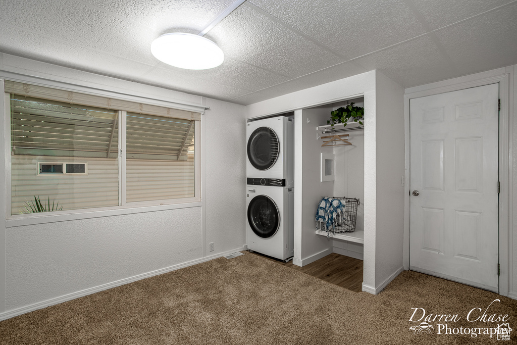 Laundry area with stacked washer and clothes dryer and carpet